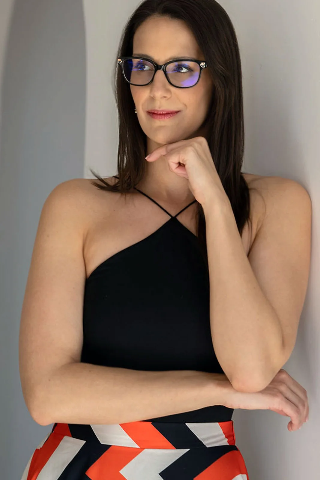 Réka szemüvegben, egy falnak dőlve, állát a kezére támasztva