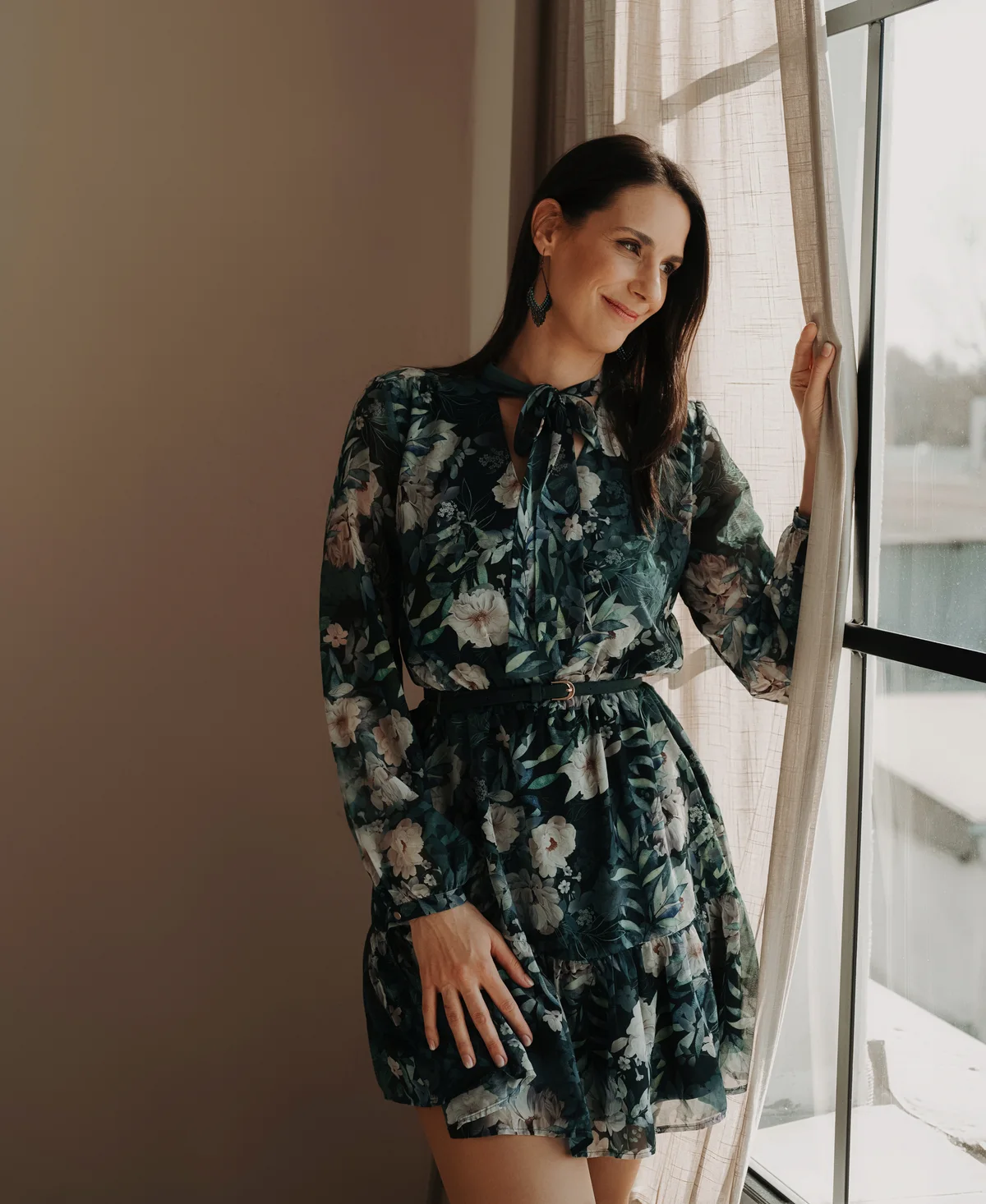 Dr. Gerhát Réka mosolyogva az ablak mellett áll, és kifelé néz
