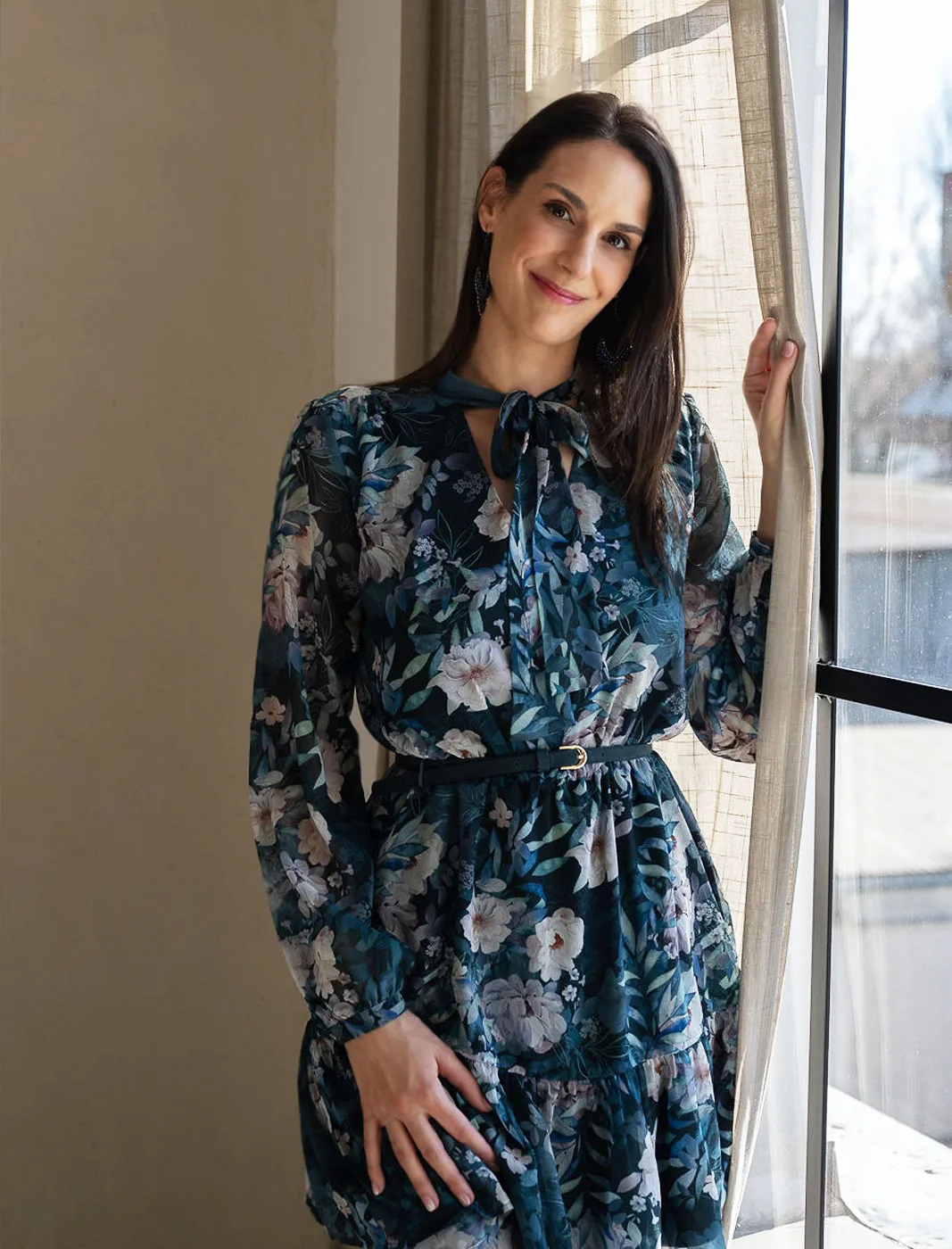 Dr. Gerhát Réka mosolyogva áll egy ablak mellett